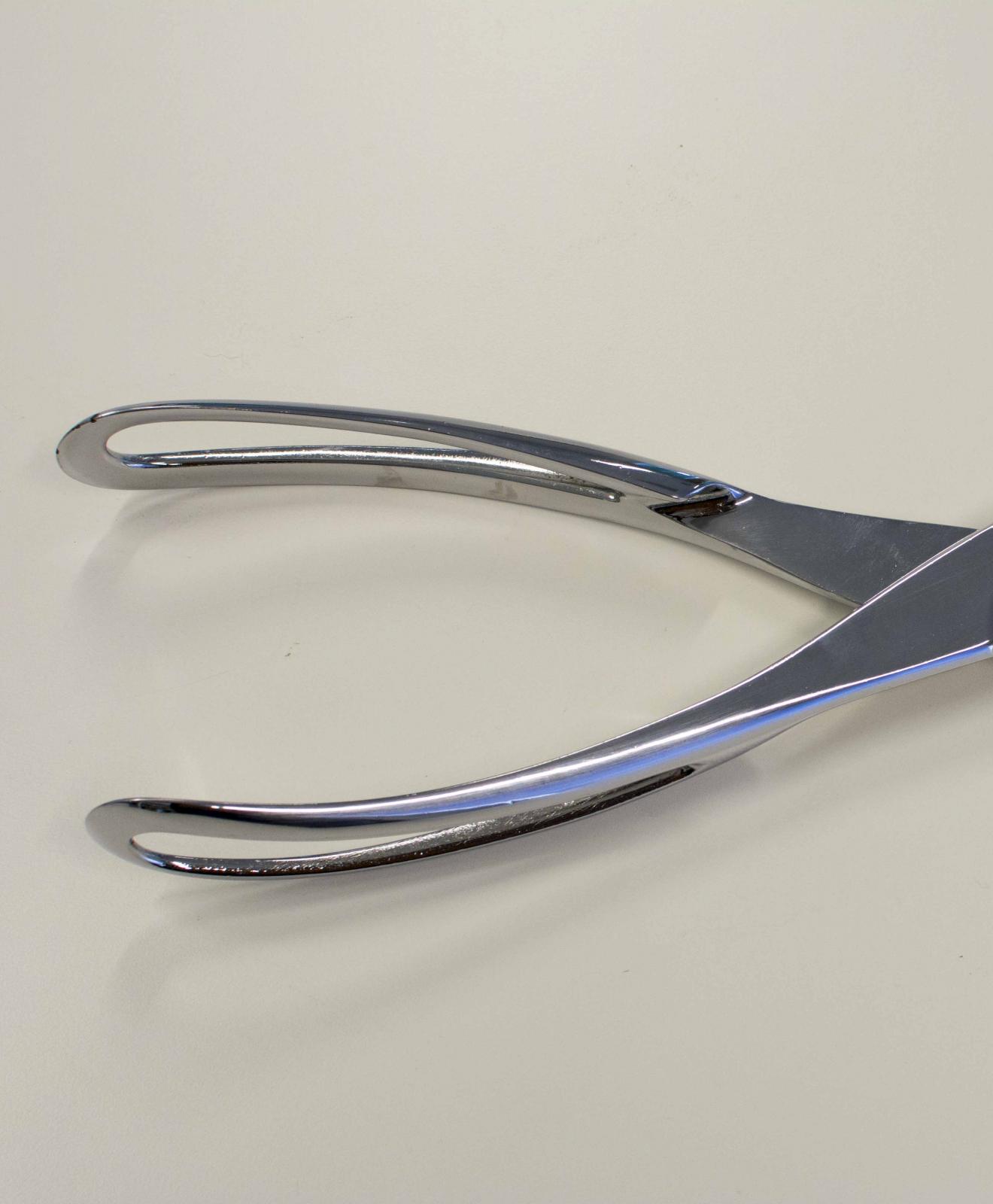 Instrumento metálico en forma de tenaza con dos ramas rematadas en un extremo con formas cóncavas y el el opuesto con mangos de agarre