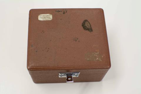 Caja marrón forrada de material imitación a piel. Cierre metálico.